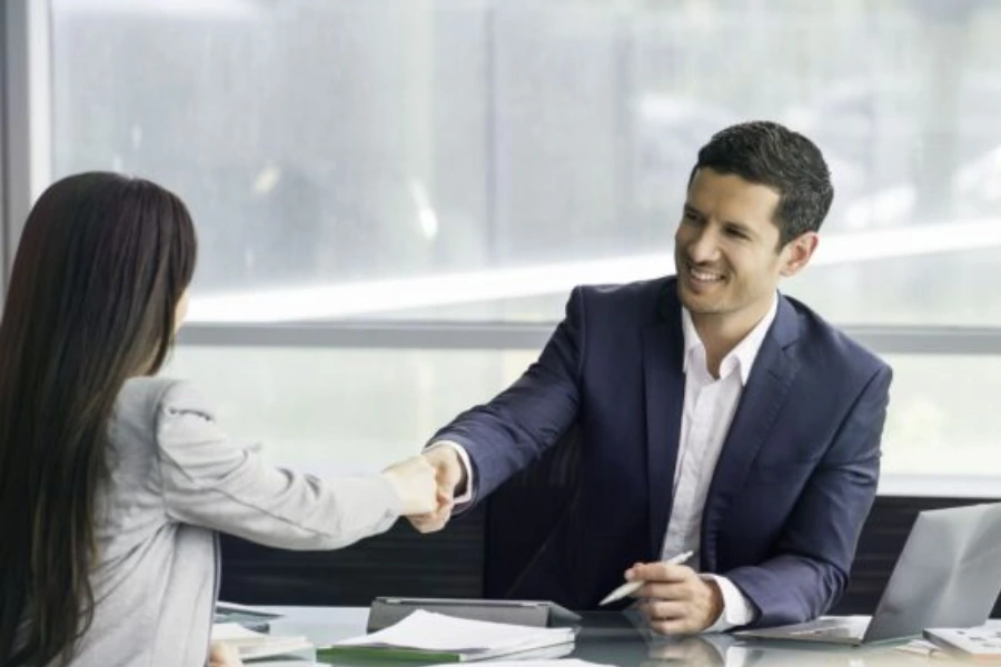 A man and woman shaking hands in an office during TheHakEvent, celebrating the Online Event of the Year.